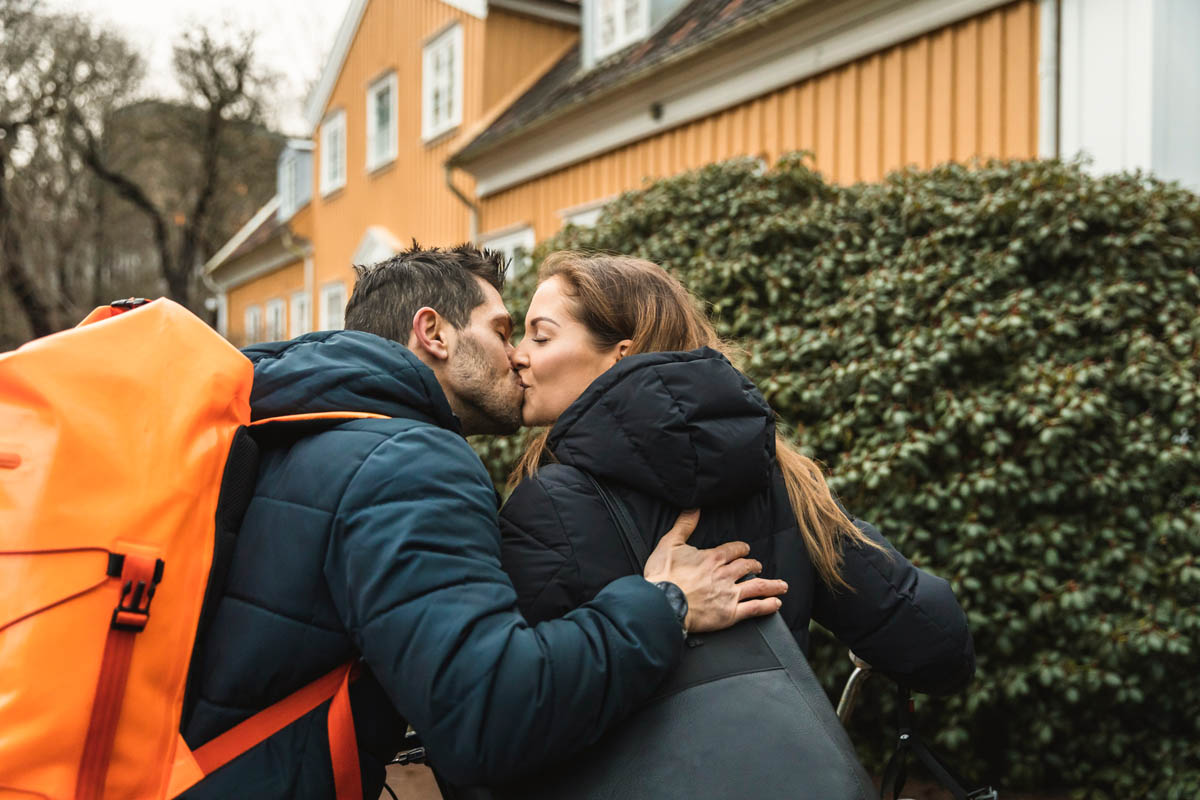 Man och kvinna kramas utomhus i bostadsområde med hus i bakgrunden