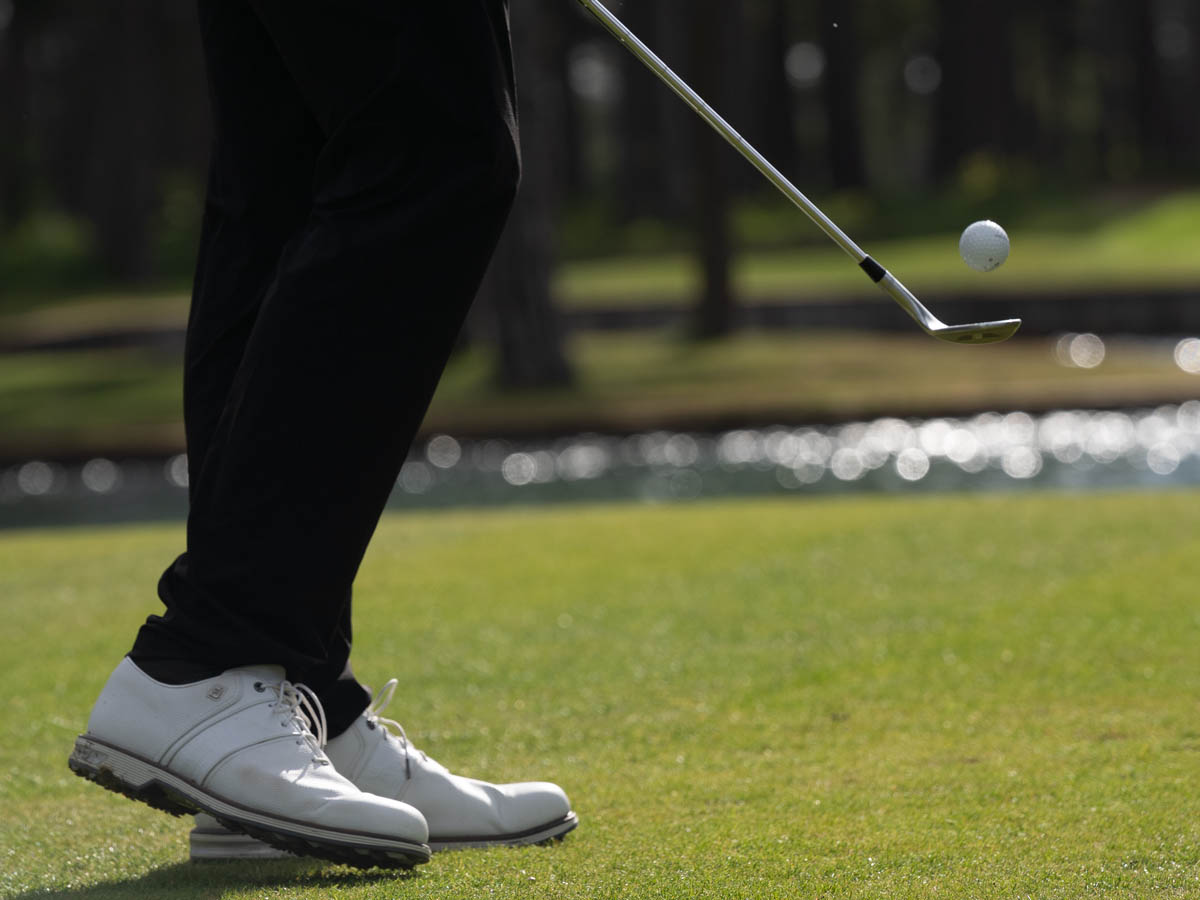 Golfspelare slår boll på green med klubba i rörelse